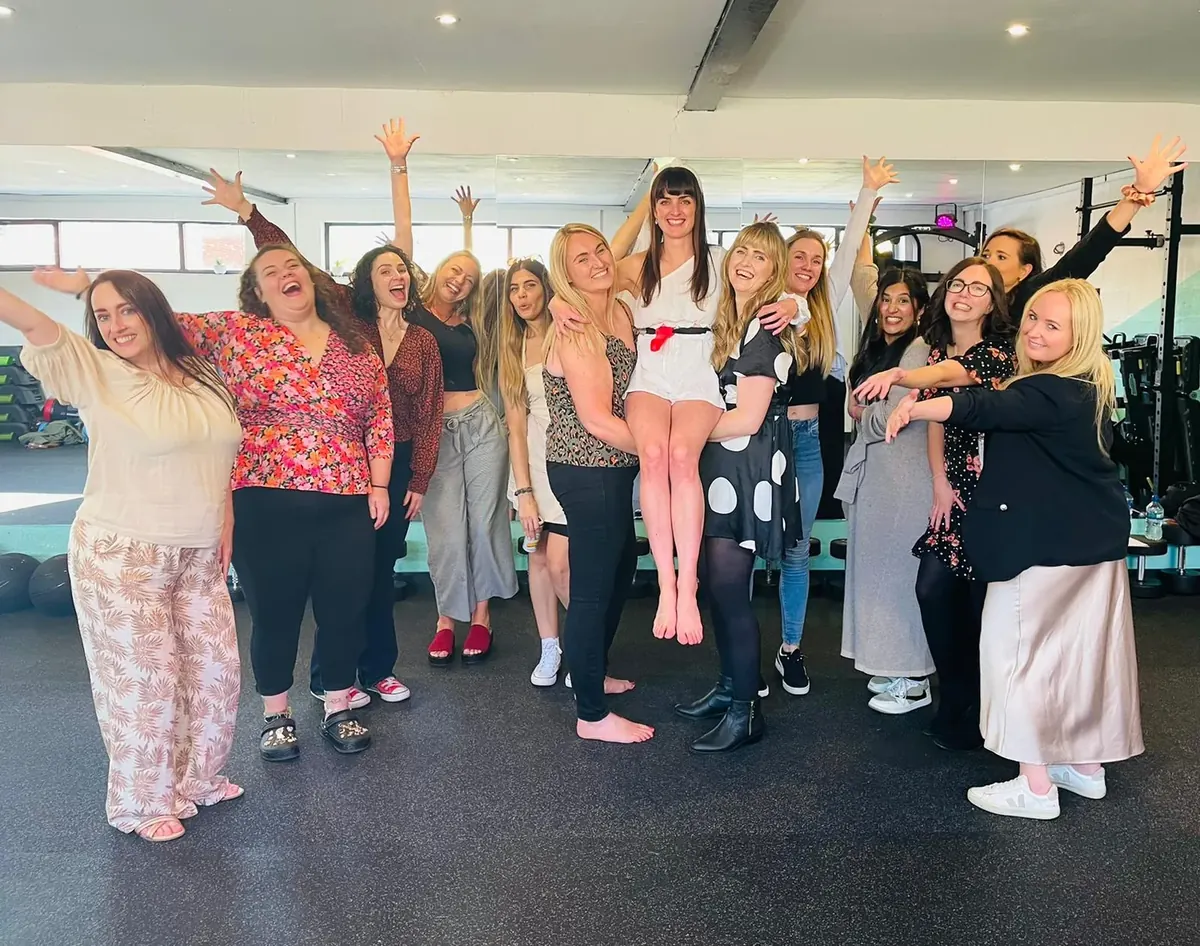 A hen group striking runway poses at a drag-inspired dance class